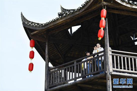  游客在重慶市武隆區(qū)黃鶯鄉(xiāng)復(fù)興村的觀景樓上欣賞田園景色（2019年3月28日攝）。 新華社記者 劉潺 攝